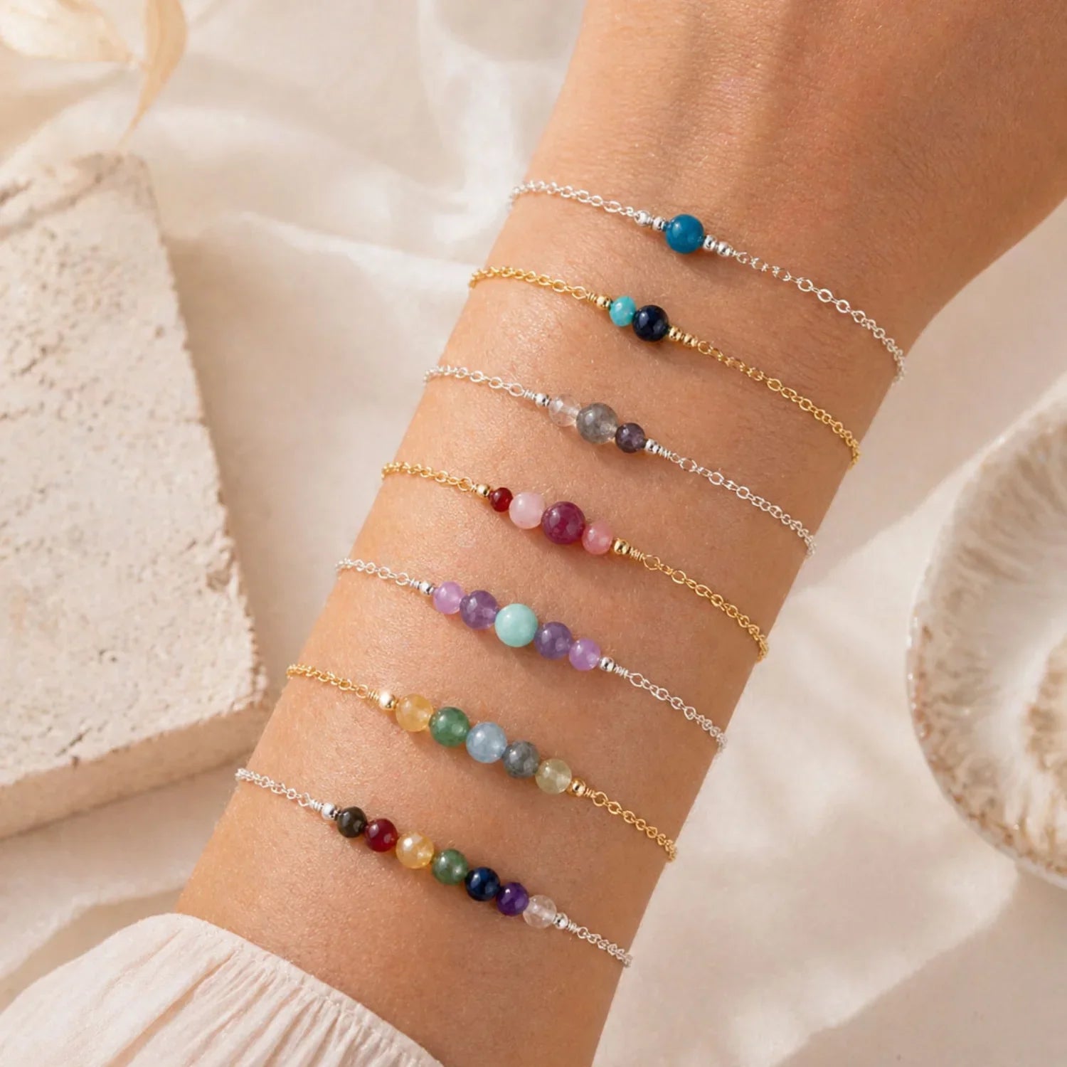 Multiple beaded bracelets on a wrist with a soft beige background